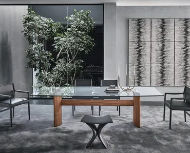 Tavolo con top in cristallo e due basi a mezzaluna in noce canaletta unite da una trave centrale in legno Beam di Porada