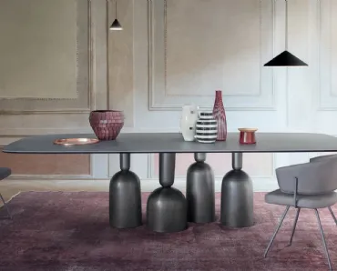 Tavolo Cop con piano in ceramica e base in metallo formata da elementi stilizzati ispirati a bottiglie, calici preziosi e coppe di champagne di Bonaldo