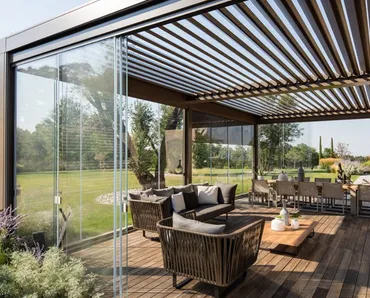 Pergola bioclimatica in alluminio con lame frangisole orientabili e pareti scorrevoli in vetro trasparente Opera di Pratic